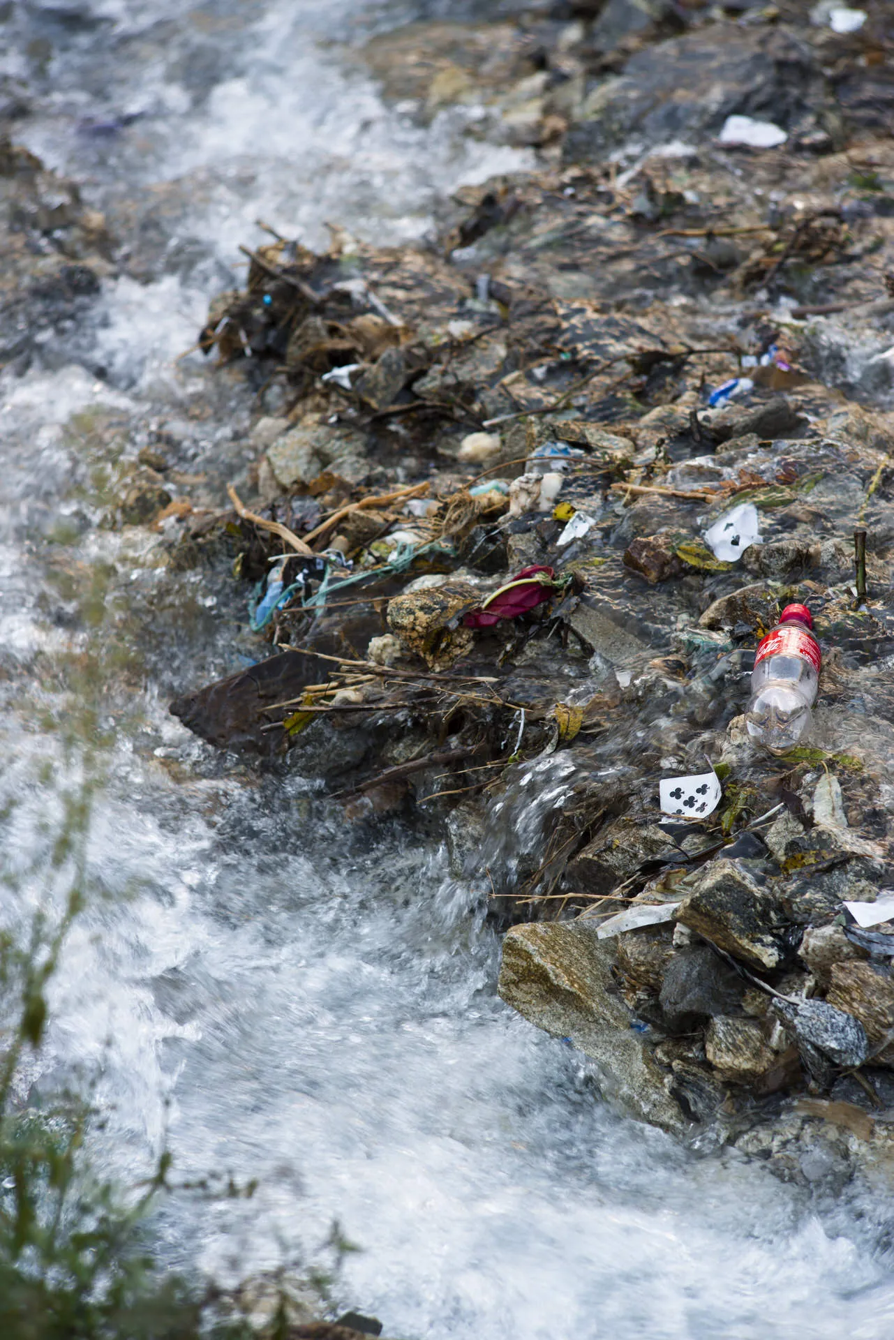 A Coca-Cola bottle and other plastic packaging caught among rocks in a rushing alpine stream in the Khumbu.