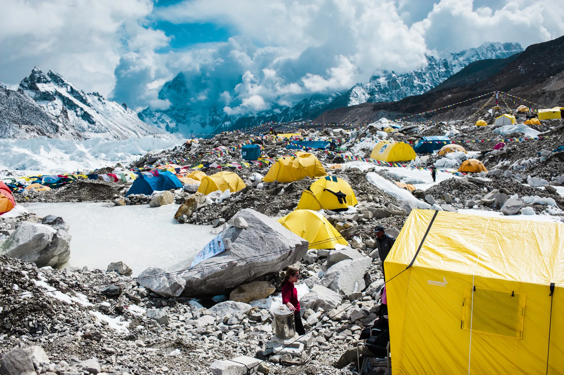 Yellow expedition tents pitched on the moraine and ice of Everest Base Camp, with snowy peaks rising behind.
