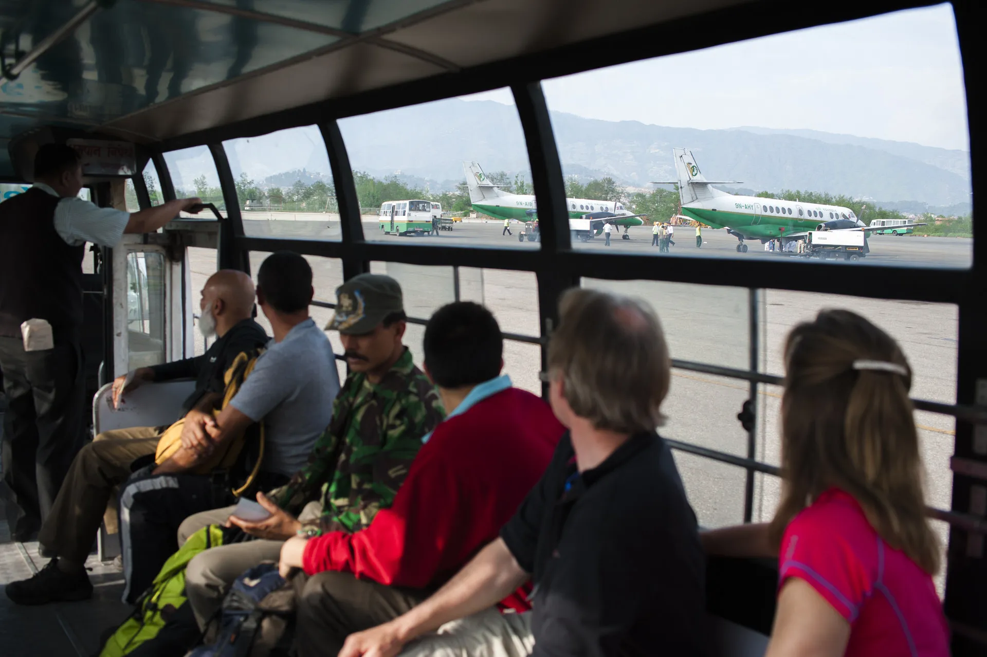 Travellers sit in an airport bus on the Kathmandu apron looking out at the small twin-prop planes that fly to Lukla.