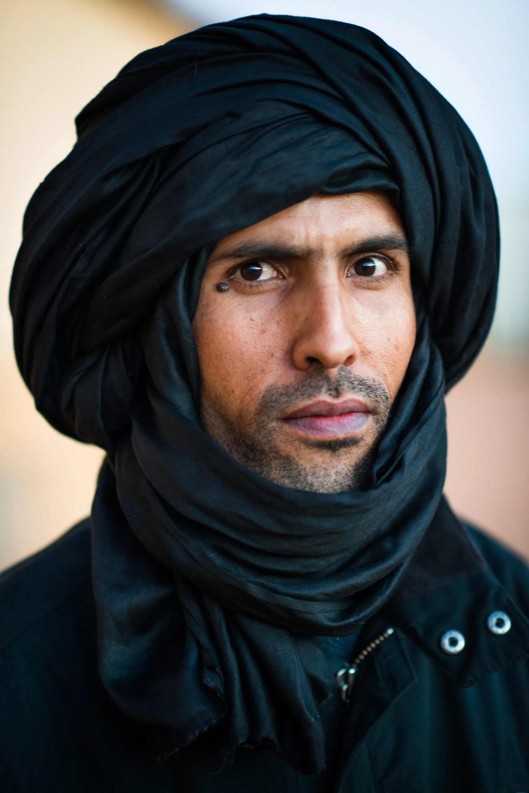 Portrait of a man in a black turban and dark jacket, with a steady gaze, in the Tindouf camps in Algeria.