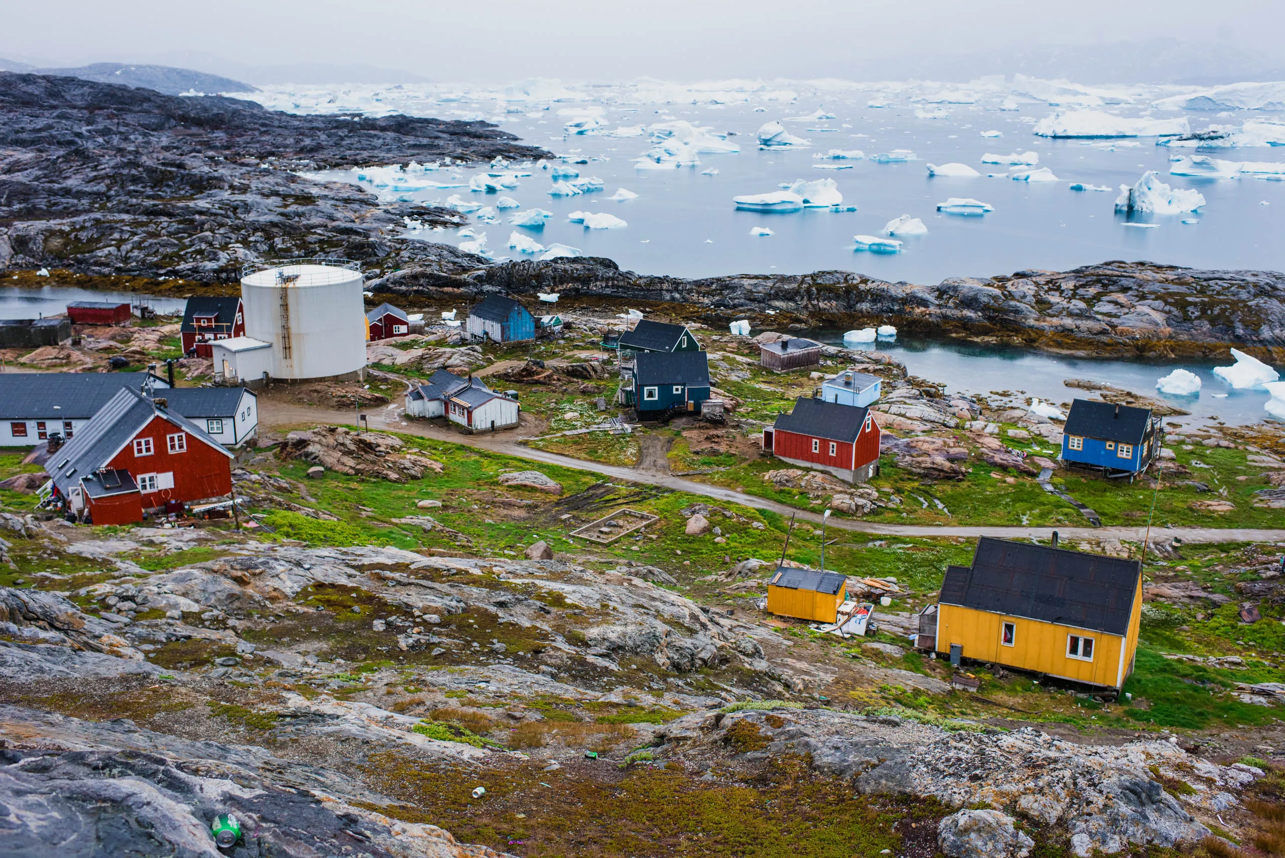 Aerial view of a small Arctic village scattered across bare rock above a frozen sea