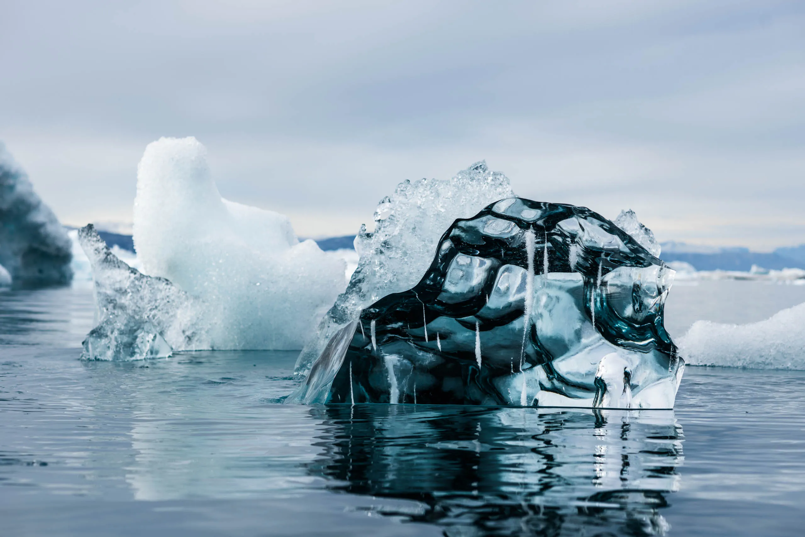 Close-up of a sculpted translucent iceberg fragment floating in calm Arctic waters