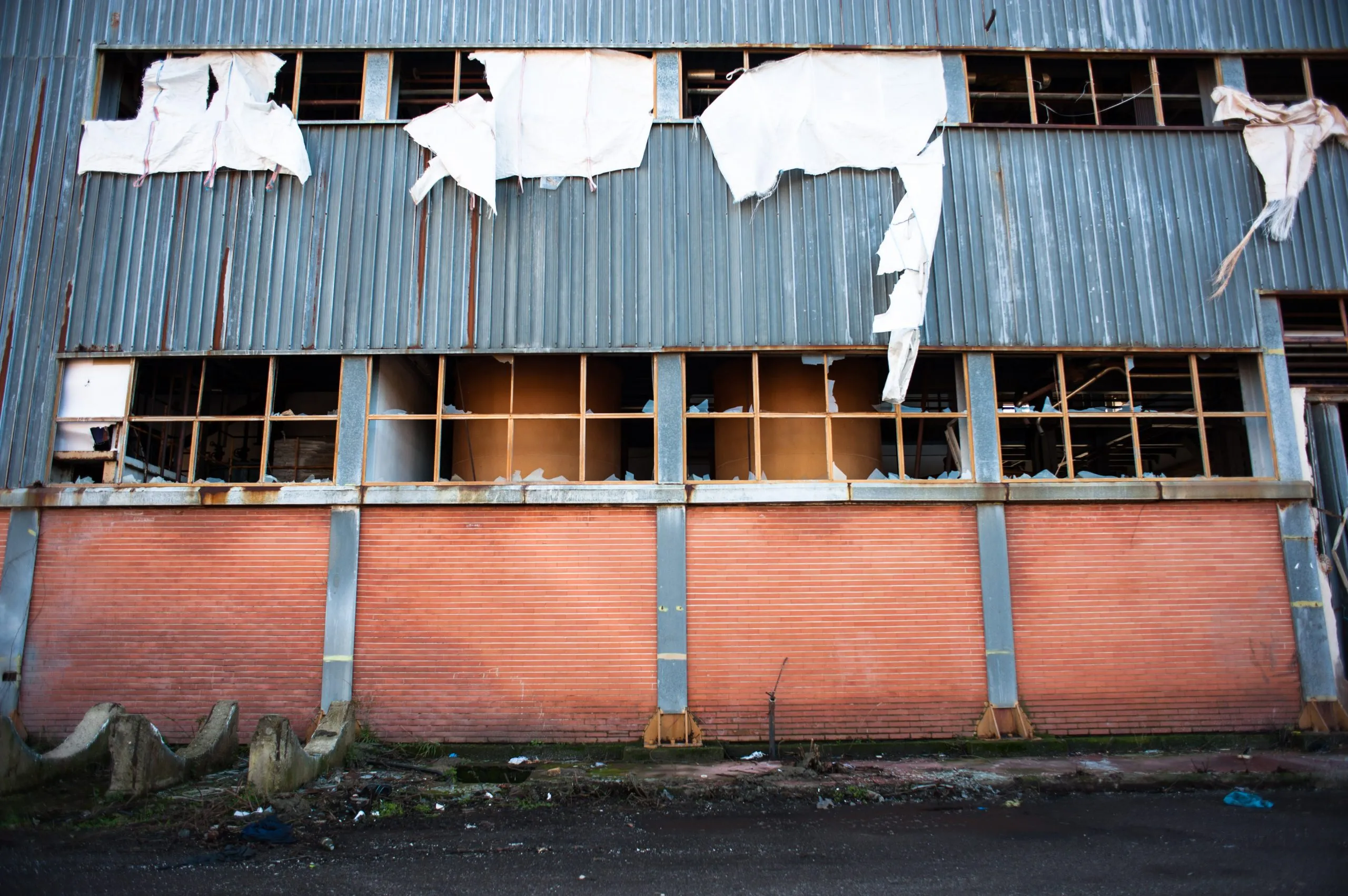 Tattered sheets hang from broken windows of an abandoned plantation warehouse in southern Italy.