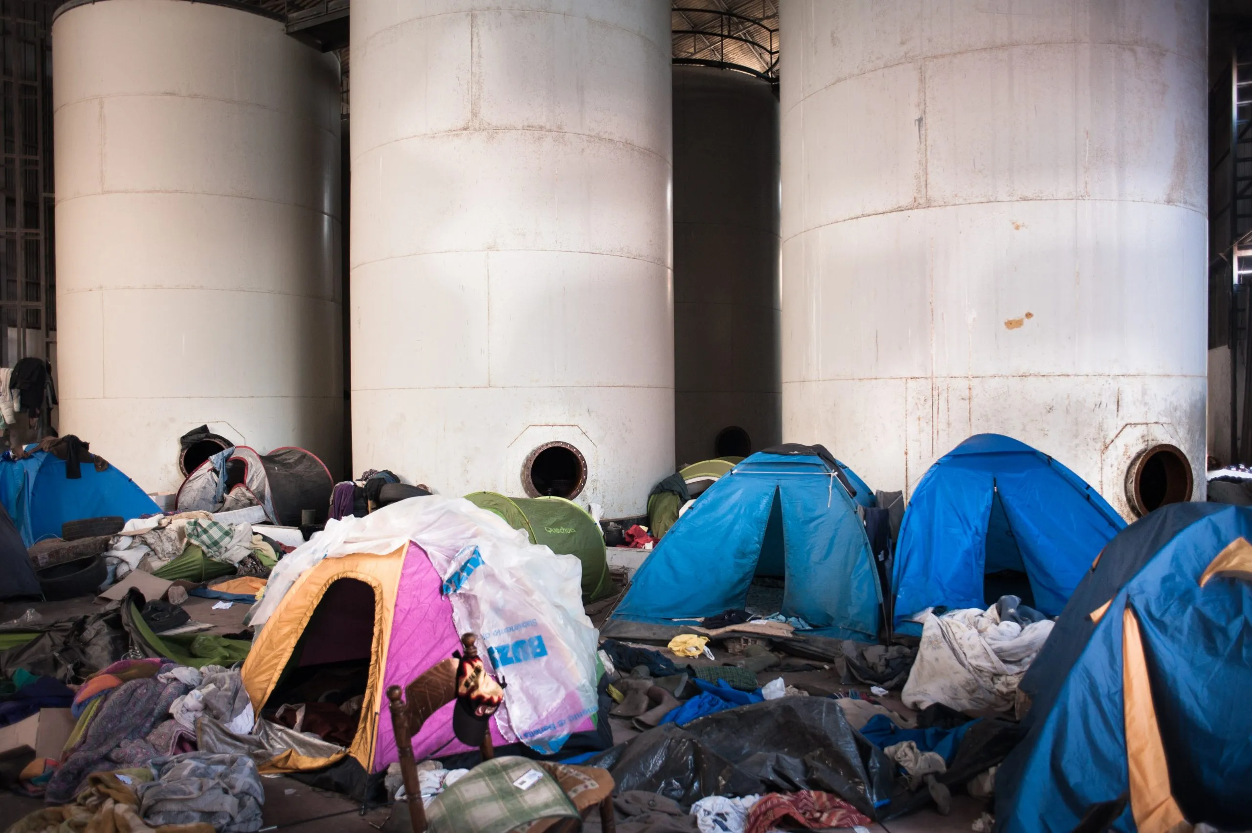 Tents pitched between large industrial silos inside the abandoned plantation warehouse in Rosarno, Italy.