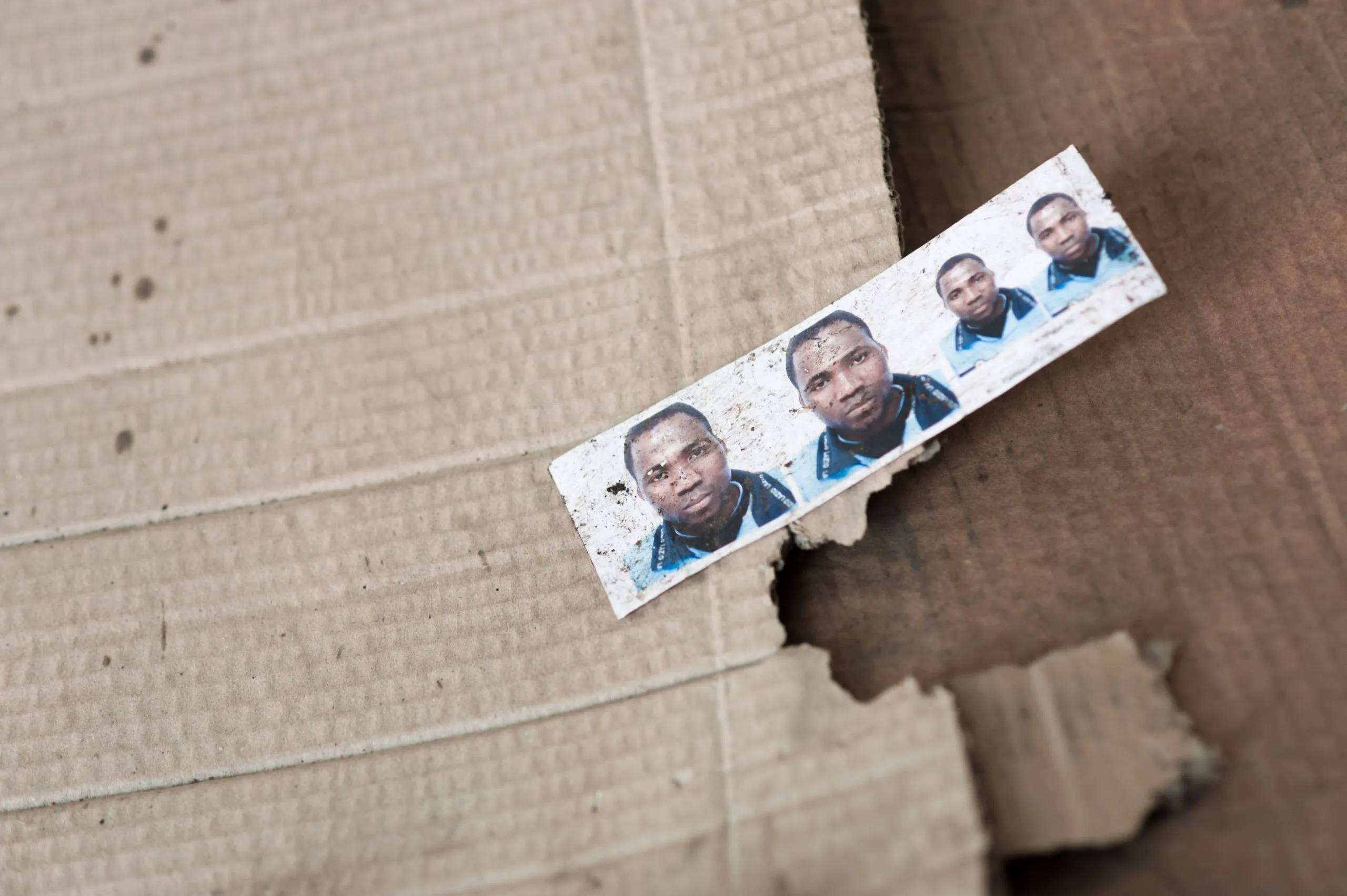 A torn passport-photo strip on a piece of cardboard, found inside the disused warehouse in Rosarno, Italy.