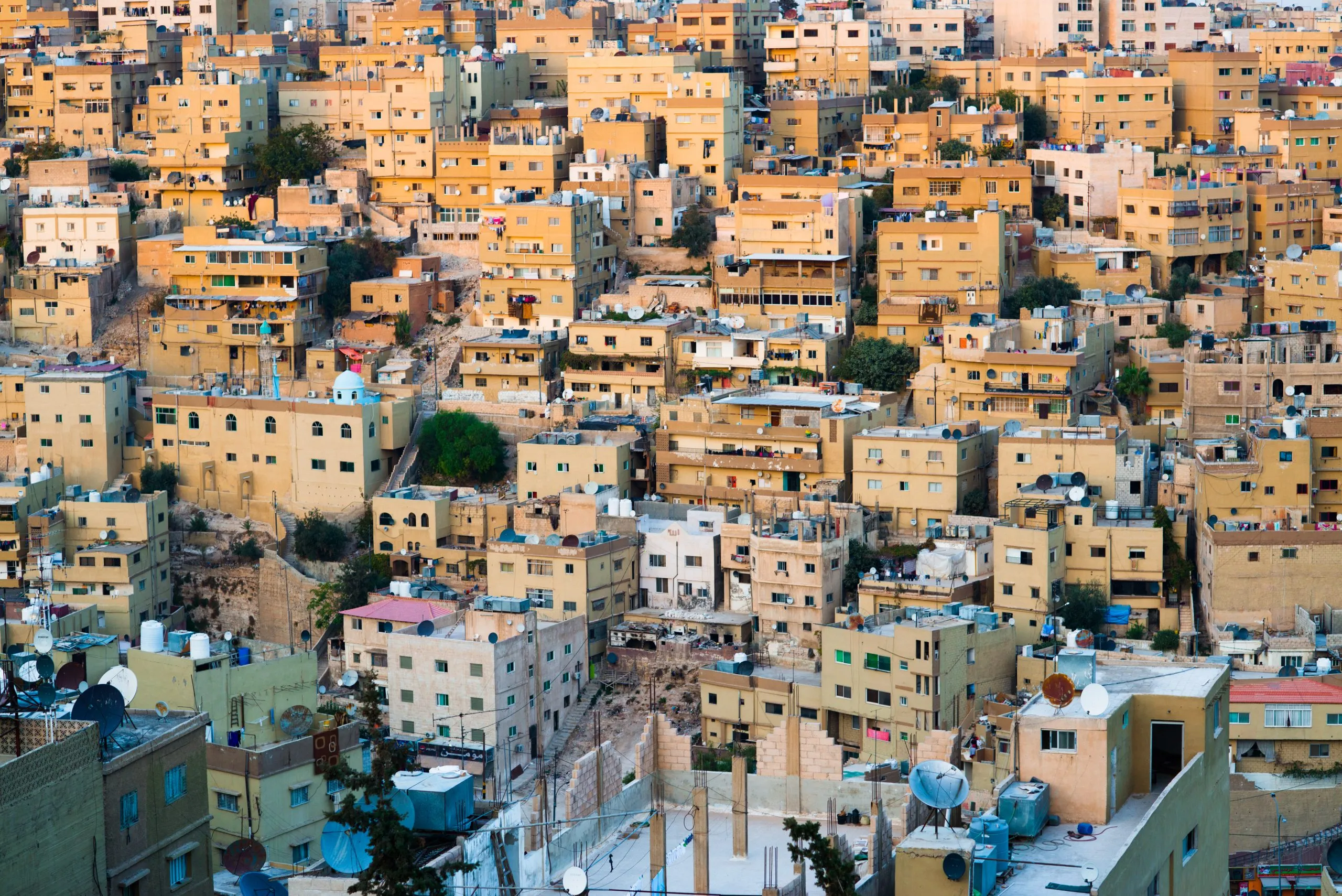 Densely-packed yellow-stone houses cover the steep hillsides of Amman, Jordan.