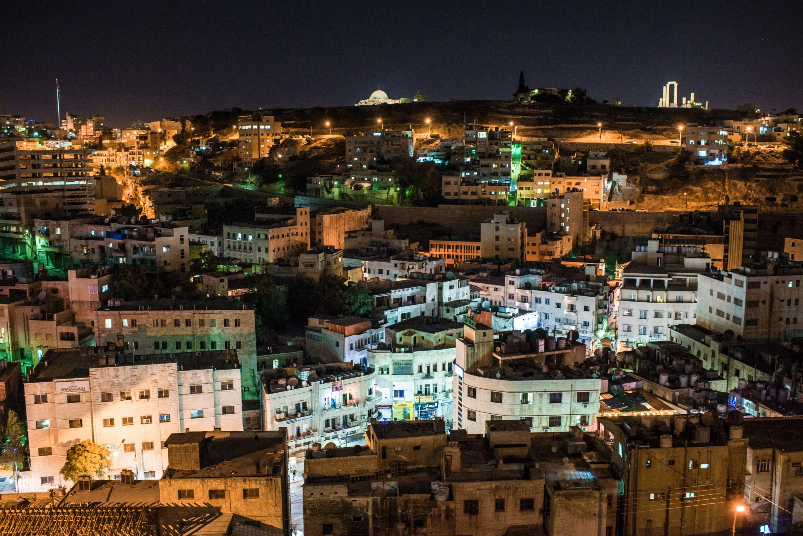 Amman at night, with the Citadel and Roman ruins lit on the hill above the dense city.