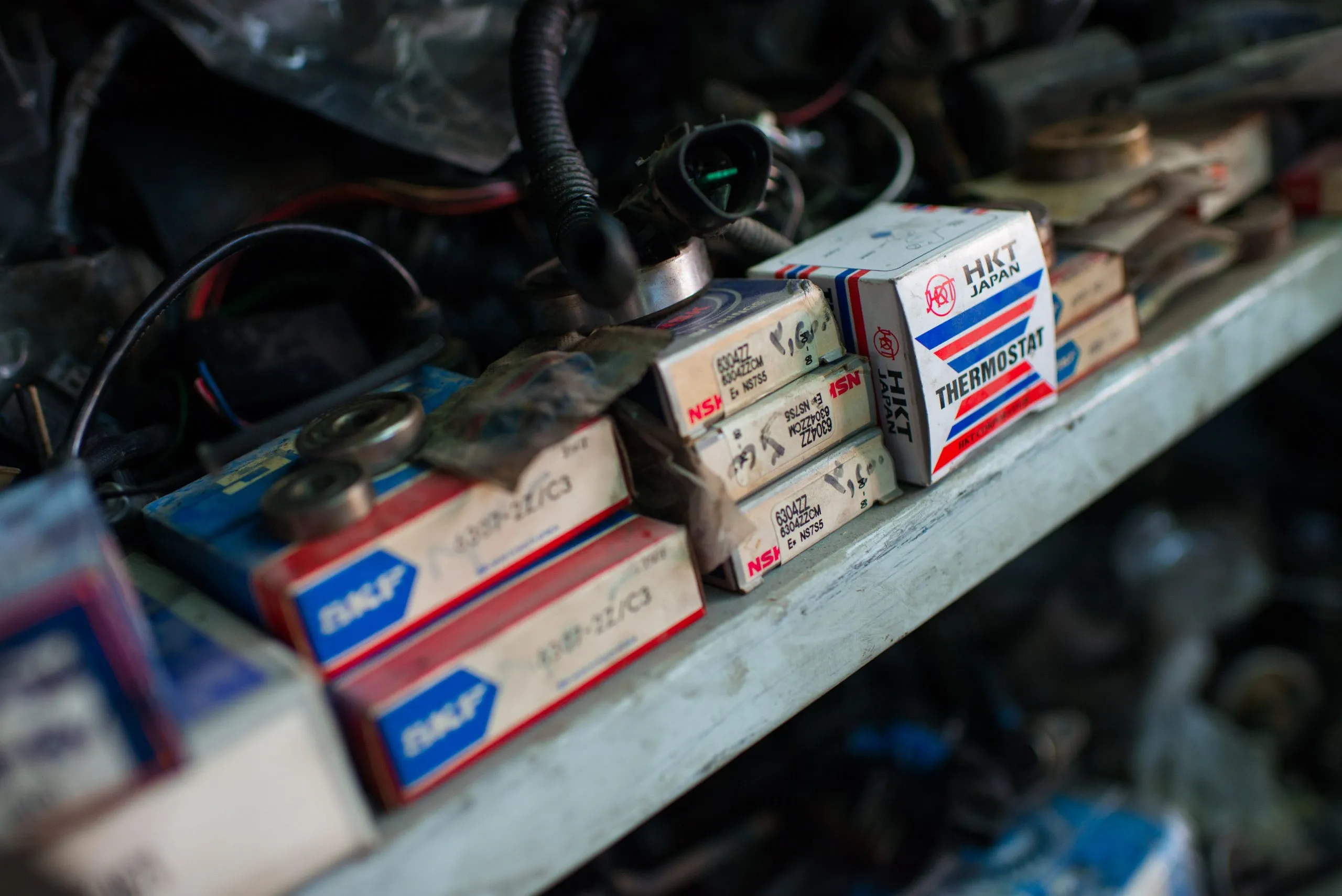 Close-up of branded SKF bearing and HKT thermostat boxes stacked on a parts-shop shelf in Amman.