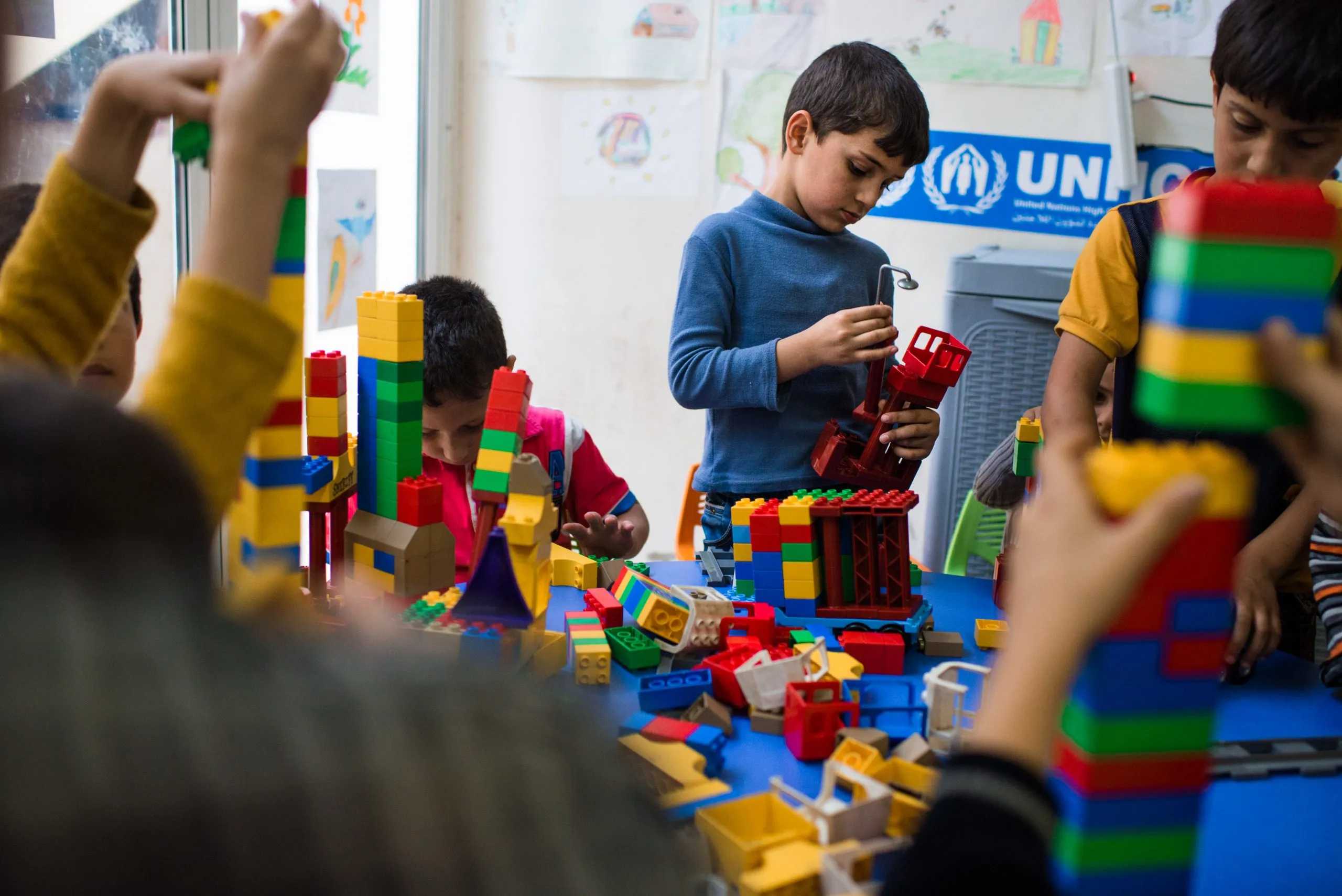 Children play with coloured building blocks at a UNHCR child-friendly space in Jordan.