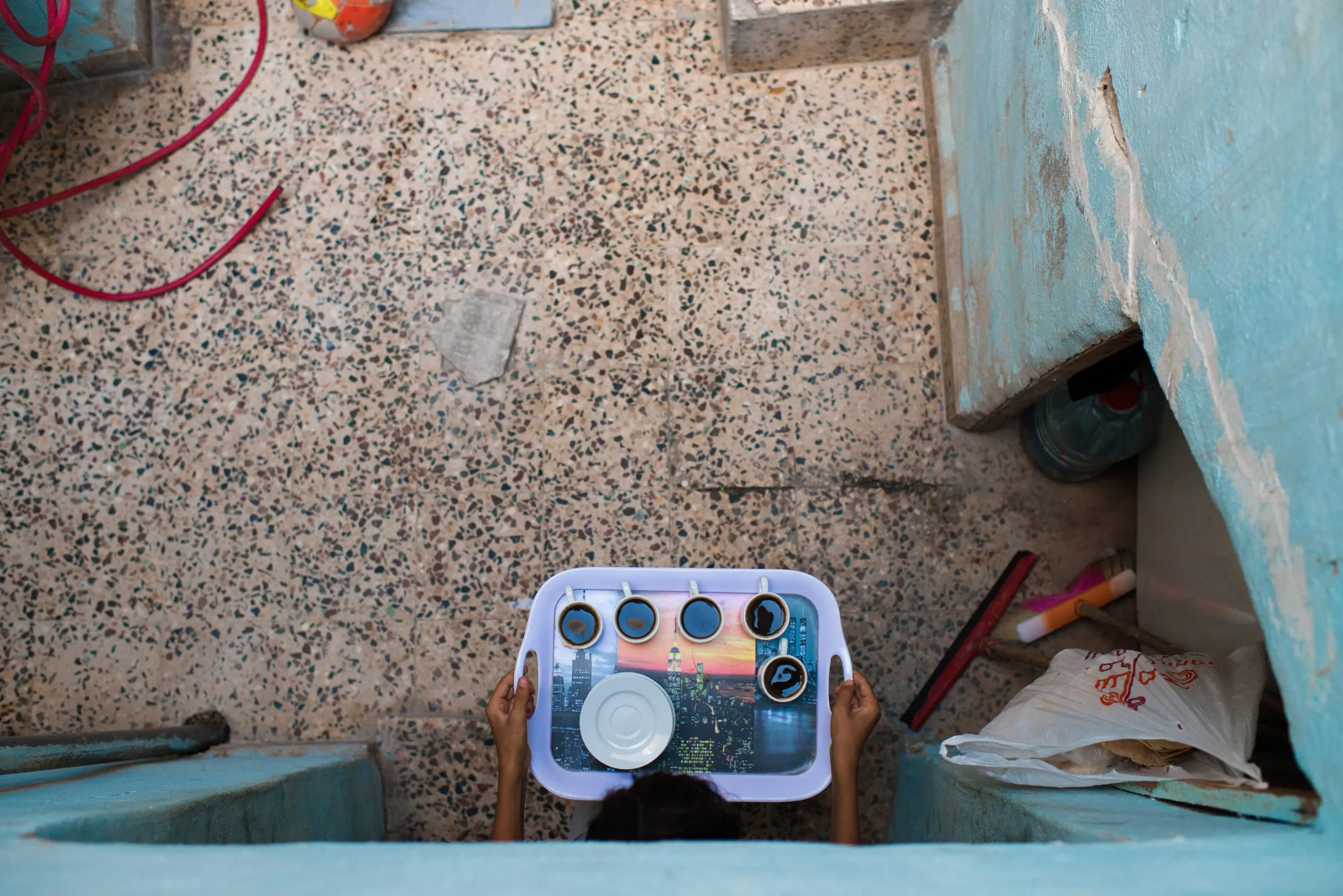 Looking down a stairwell at a child holding a small printed toy radio in their hands, in Jordan.