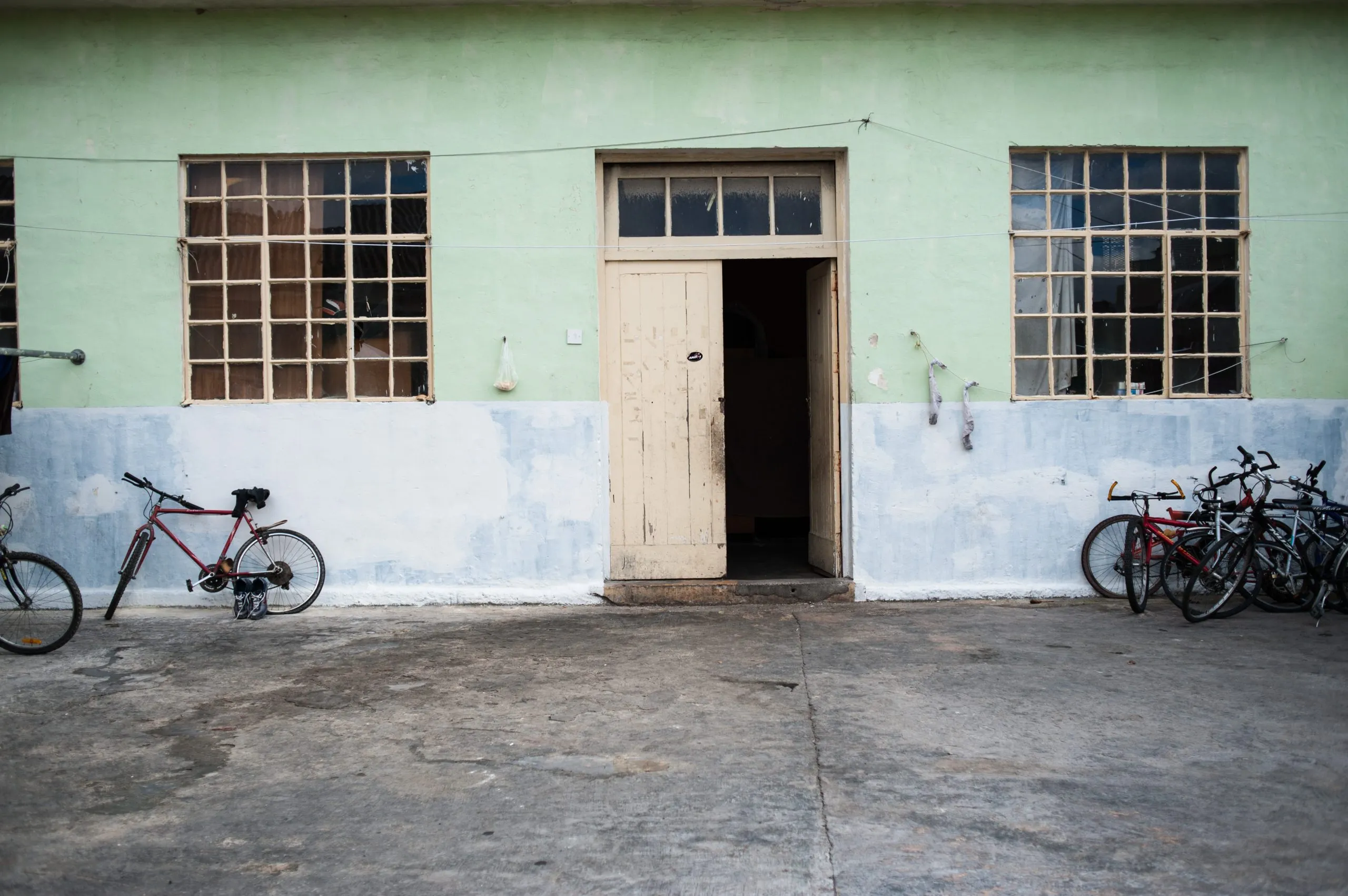 An open doorway in the painted green facade of a residential block on Malta, with bicycles leaning beside it.