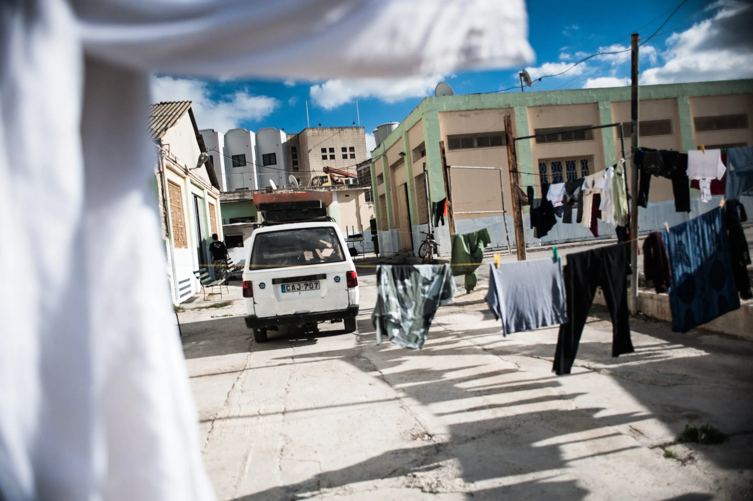 A courtyard with hanging laundry and a parked white van, at the housing compound on Malta.