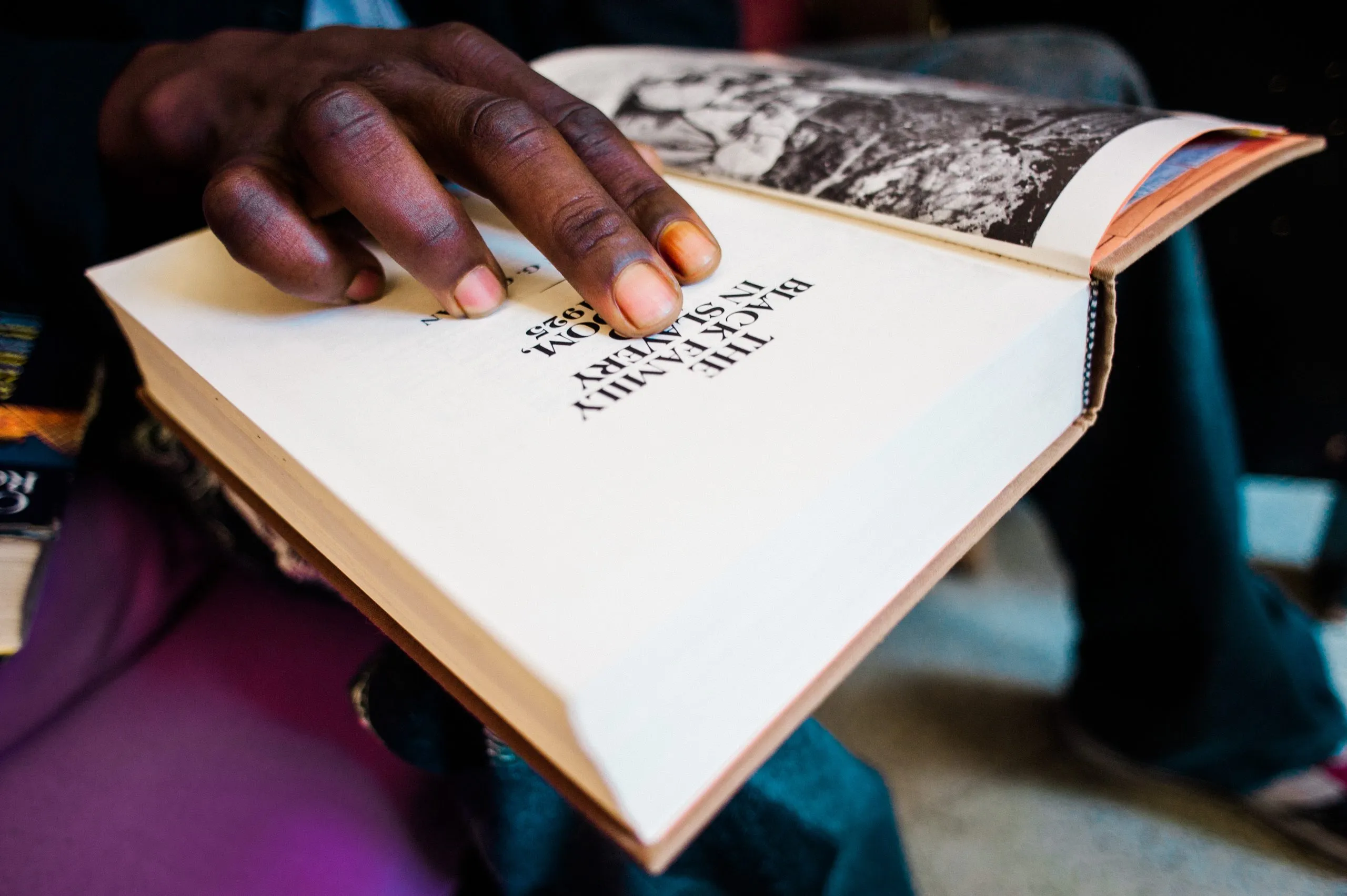 A hand resting on the open page of a book titled "The Black Family in Slavery".