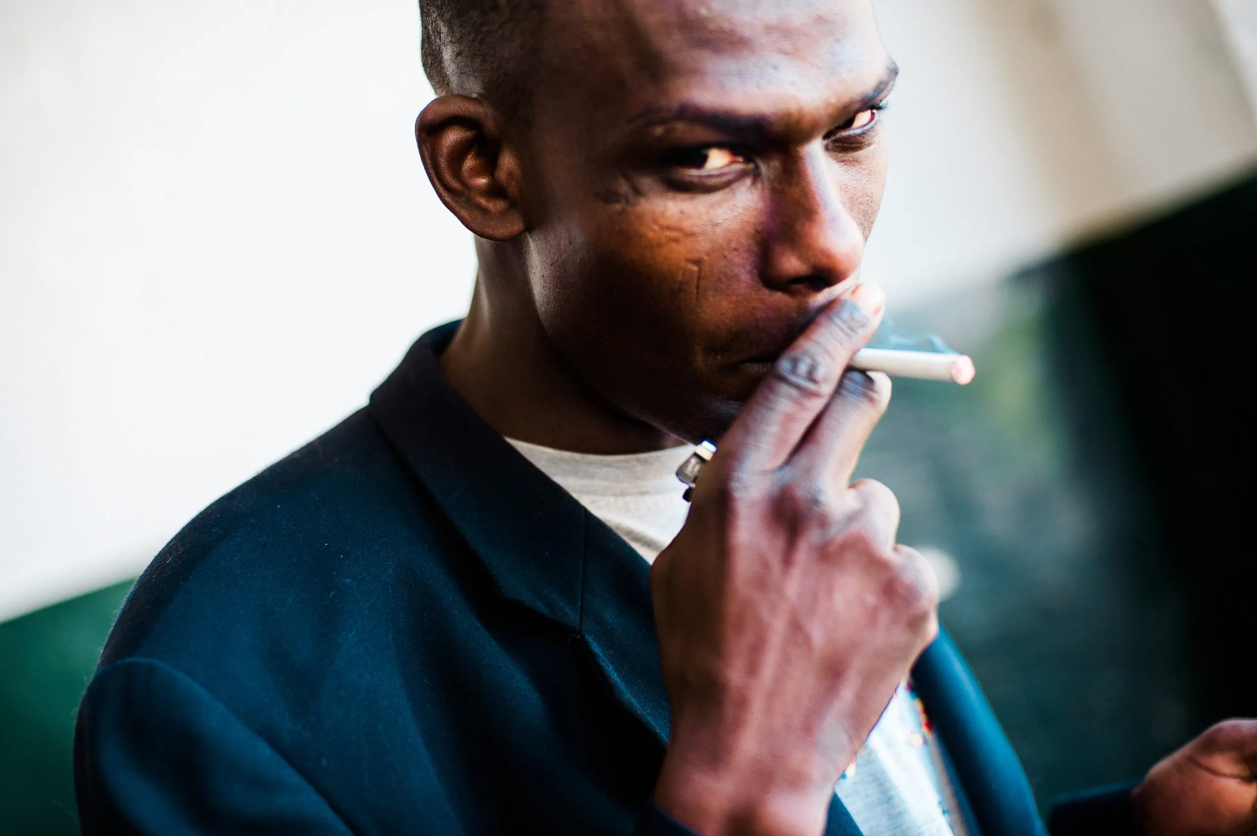 A close portrait of a man smoking a cigarette inside the housing hangar in Malta.
