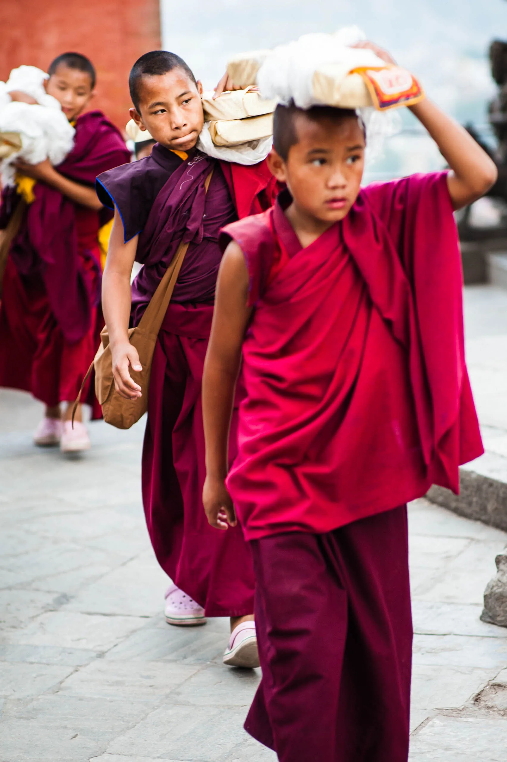 A young monk carries a bundle of white khata scarves and butter-lamp boxes for the evening ceremony at Swayambhunath.