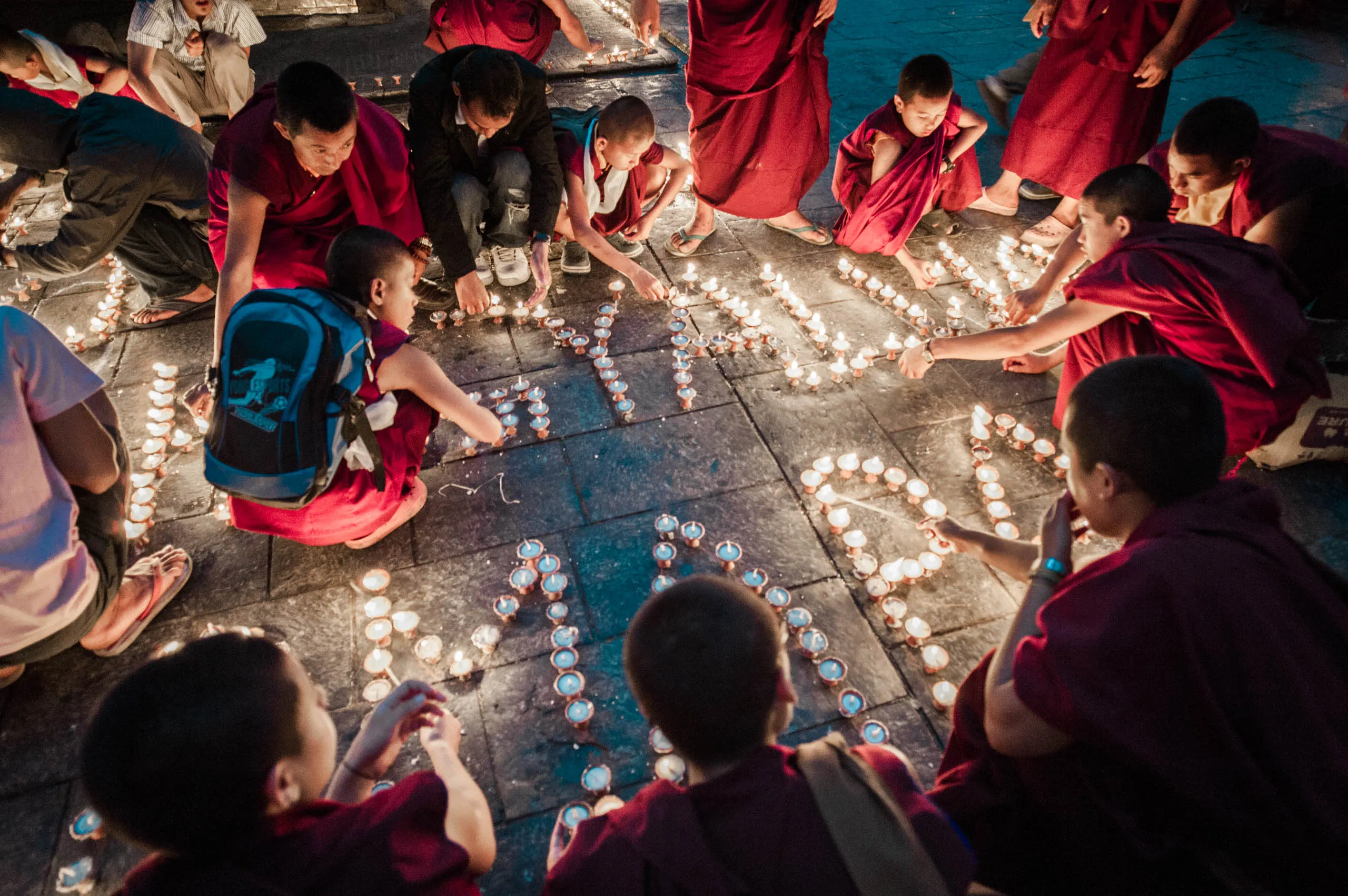 Monks crouch around a large pattern of butter lamps laid out across the temple floor at Swayambhunath.