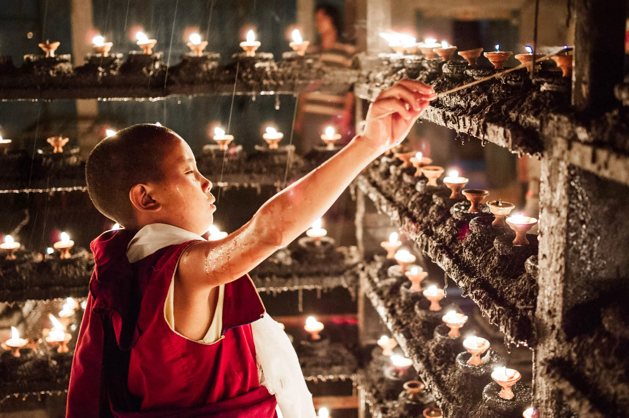 Monks work together to light butter lamps shaped into Tibetan script across the courtyard at Swayambhunath.