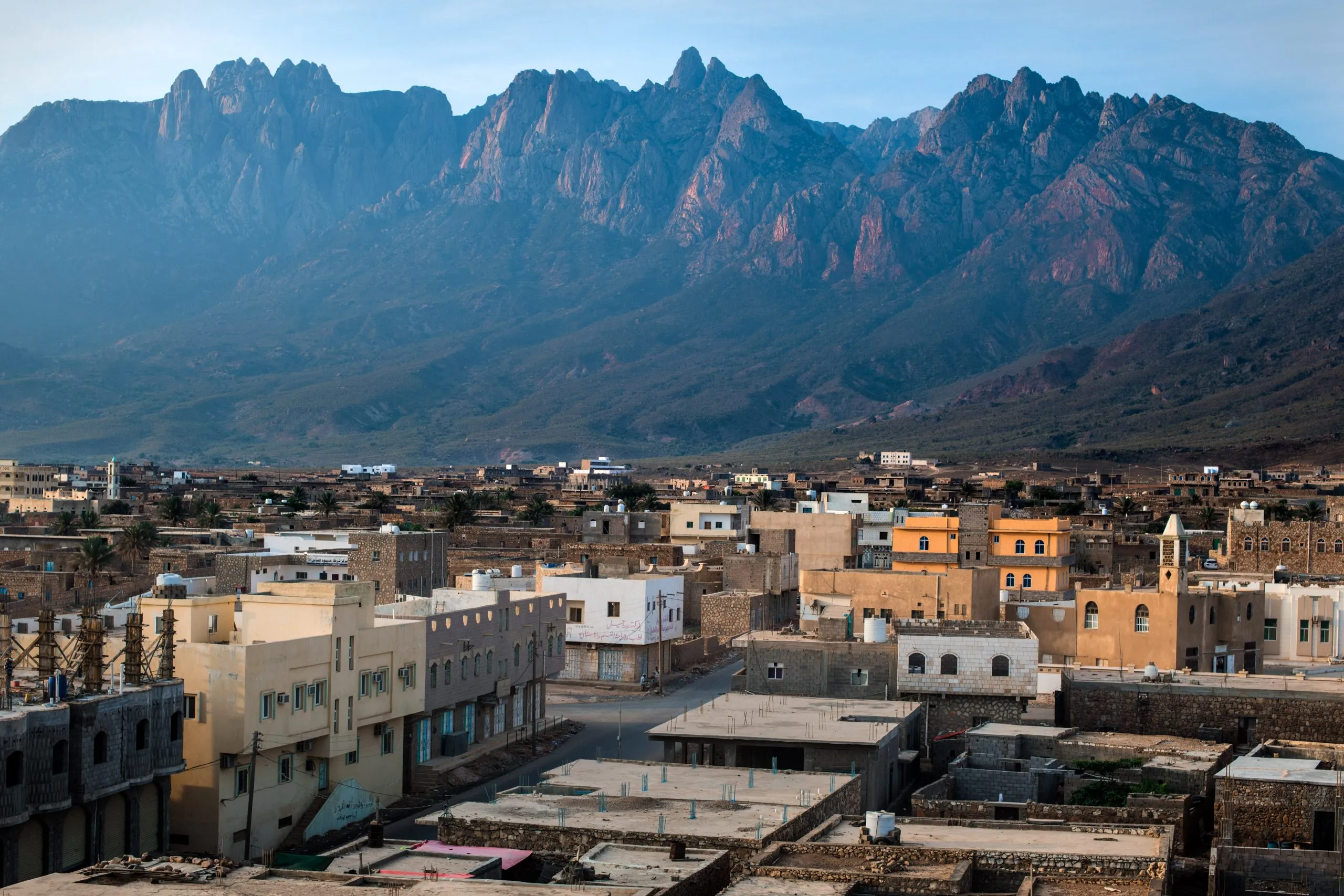 View at dawn over the rooftops of Hadibu with the jagged peaks of the Haghier Mountains rising sharply behind the town.