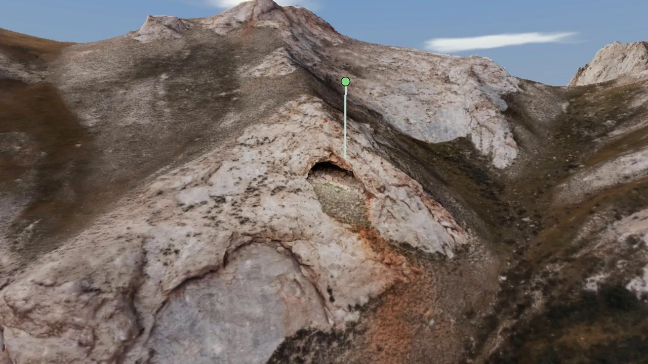 A cave opening in a limestone slope in Kok-Kiya, Kyrgyzstan, marked with a pin in a photogrammetry model.